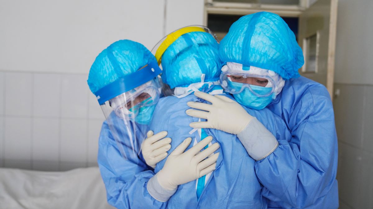 Медици в защитно облекло се прегръщат в болнично отделение Медици в защитно облекло се прегръщат в болнично отделение